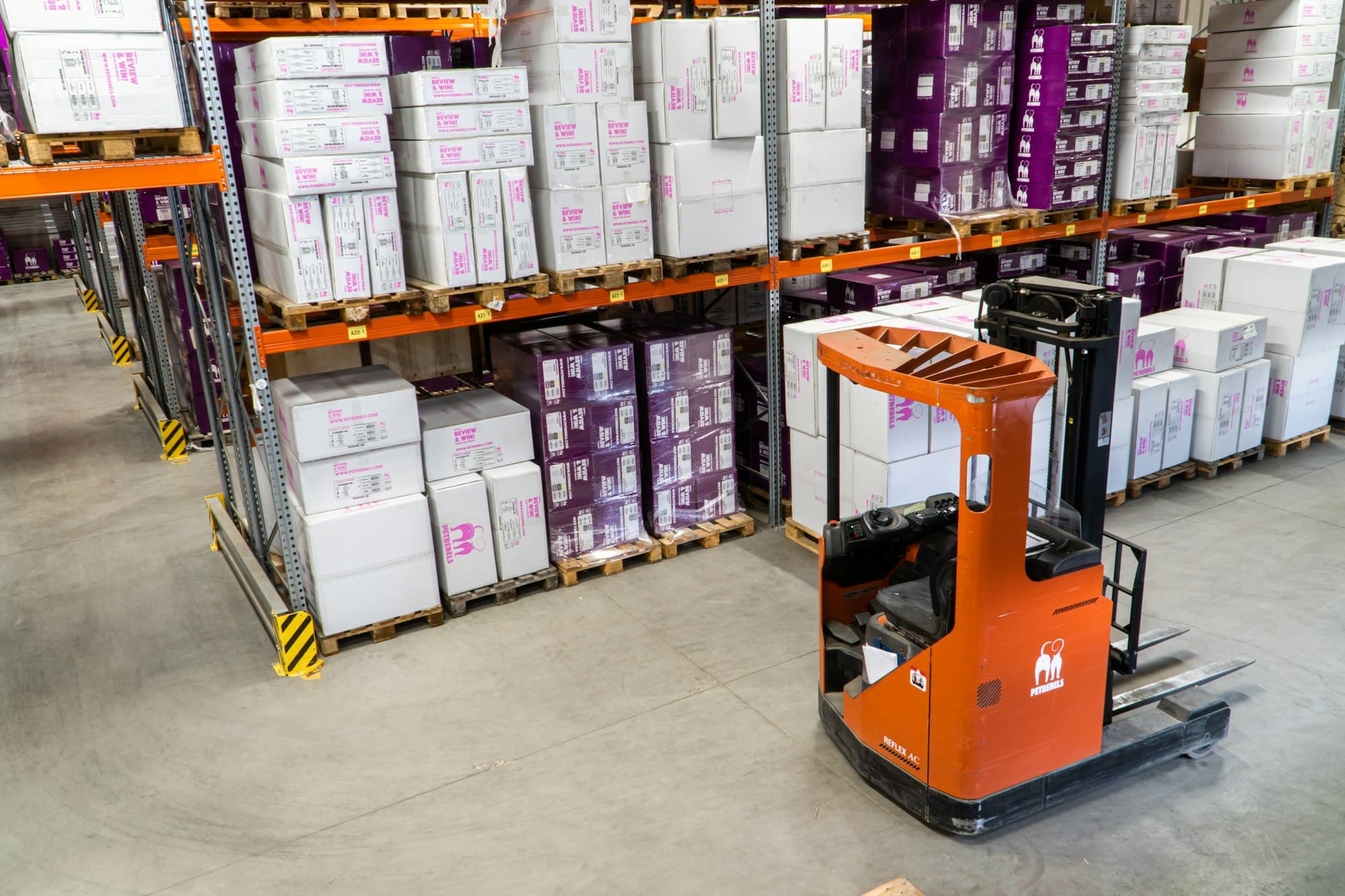 Electric forklift between stacked warehouse shelves
